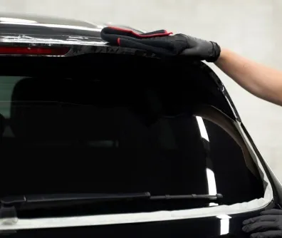 Instalador aplicando película no vidro traseiro de um SUV preto
