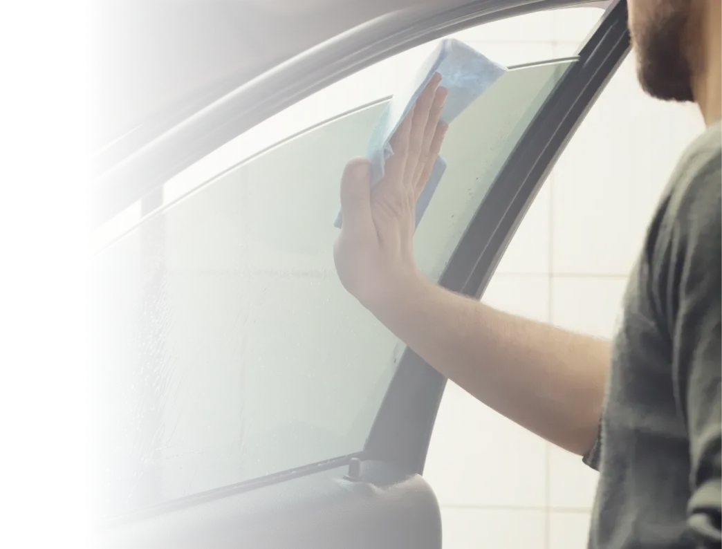 Instalador alisando o insulfilm no vidro da porta de um carro